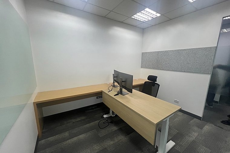 A private room with an L-shaped desk, chair and monitor.